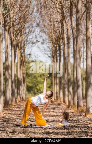 Fröhliche Mutter und Tochter üben Yoga im Park während der Sonne Tag Stockfoto