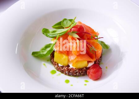 Zartes Lachsfilet auf einem Quinoa-Kissen mit Gemüse. Speisekarte im Restaurant. Weißer Hintergrund. Freier Speicherplatz für Text. Stockfoto