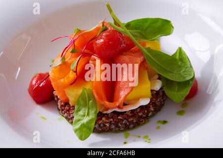 Zartes Lachsfilet auf einem Quinoa-Kissen mit Gemüse. Speisekarte im Restaurant. Weißer Hintergrund. Freier Speicherplatz für Text. Stockfoto