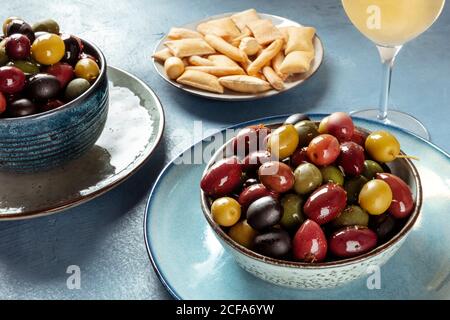 Oliven, Brotstangen und Weißwein an einer Bar. Eine Vielzahl von grünen, schwarzen und roten Oliven Stockfoto