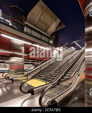 Langzeitaufnahme des modernen mehrstöckigen Bahnhofs mit Rolltreppe Und rote und blaue Wände und graue hohe Säulen in Spanien Stockfoto