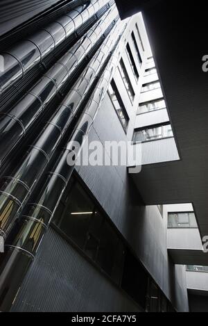 Von unten vom Hof des zeitgenössischen hohen Gebäudes mit Metall Rohre und Fenster Stockfoto