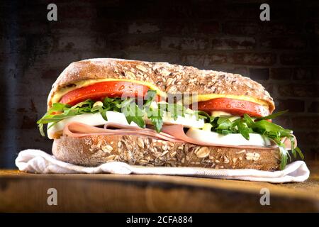 Nahaufnahme von köstlichen Sandwich mit Vollkornbrot gefüllt mit gemacht Salat gekochtes Ei und Schinken auf Holzbrett serviert Schwarzer Hintergrund Stockfoto