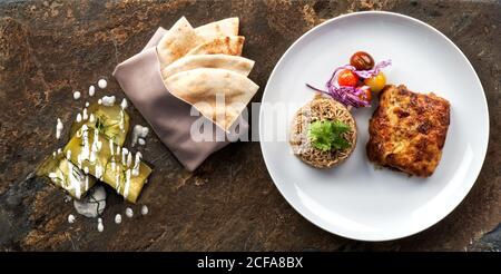 Draufsicht auf den Teller mit traditioneller libanesischer Moussaka serviert Reis und Gemüse mit typischen Fladenbrot auf den Tisch gelegt Stockfoto