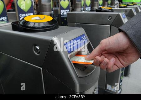 Hand setzen Zug-Ticket in eine TFL-Stationen Ticket Barriere im Großraum London. Stockfoto