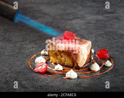 Nahaufnahme eines raffinierten türkischen Gerichts mit Wagyu-Rinderfilet Serviert auf einem Stück Gebäck und garniert mit Chili-Creme Sauce und Joghurt mit marinierten Zwiebeln, die mit Fackel gegrillt werden Brenner Stockfoto