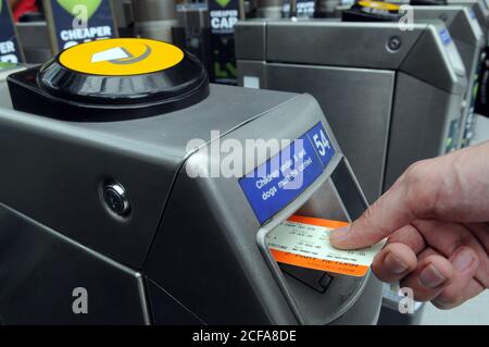 Hand setzen Zug-Ticket in eine TFL-Stationen Ticket Barriere im Großraum London. Stockfoto