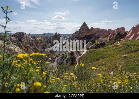 Spitze der rauen Felsformation in erstaunlicher Landschaft und entfernte Stadt in Kappadokien, Türkei an einem sonnigen Tag Stockfoto