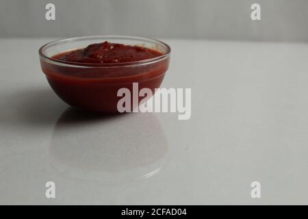 Rote Tomate heiß oder süß Sauce wird in einem gegossen Glas Topf Schüssel Teller auf einem weißen grauen Hintergrund Kopie Platz Stockfoto