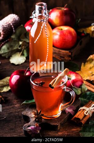 Heißer Apfelessig mit Zimtstangen, Nelken und Anis auf Holzgrund. Traditionelle Herbstgetränke, Wintergetränke und Cocktails Stockfoto