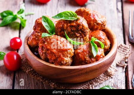 Fleischbällchen mit Tomatensauce und Basilikum, Vintage-Holzhintergrund, selektiver Fokus Stockfoto