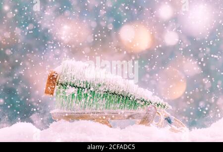 Kleiner Weihnachtsbaum auf Holzschlitten oder Schlitten, Silvester verschneiten Hintergrund, Weihnachtskonzept Stockfoto