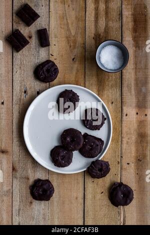 Von oben aromatische Kekse mit Schokoladensirup in weiß bedeckt Teller auf Holztisch Stockfoto