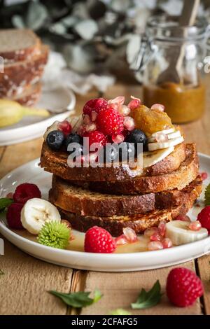 Honig gießt über gebratene Toast mit Obst Stockfoto