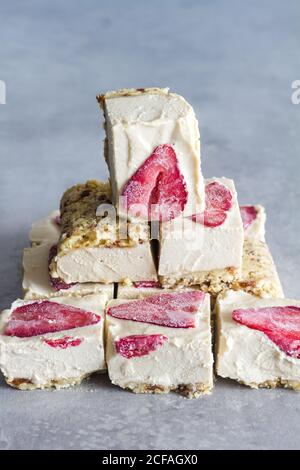 In Stücke schneiden köstliches hausgemachtes Frostdessert mit weißer Sahne Und in Scheiben geschnittene Erdbeere auf Marmorboden Stockfoto