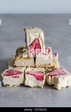 In Stücke schneiden köstliches hausgemachtes Frostdessert mit weißer Sahne Und in Scheiben geschnittene Erdbeere auf Marmorboden Stockfoto