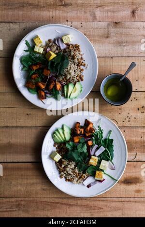 Draufsicht auf vegetarisches Essen mit verschiedenen Gemüse und Reis Auf Tellern auf rustikalem Holztisch Stockfoto