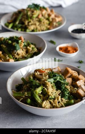 Von oben schmackhafte gekochte Gericht mit Reis und grünen Bohnen Servieren auf Tellern mit Gewürzen auf dem Tisch Stockfoto