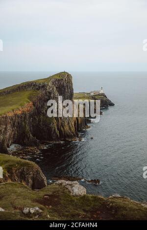 Von oben majestätischer Blick auf Neist Point Leuchtturm gebaut Hohe Felsen umgeben von dunklem Wasser am Tag Stockfoto