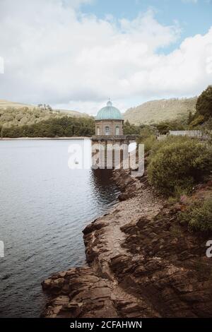 Malerische Flusslandschaft zwischen Felsen und einer Kuppelspitze, die tagsüber unter bewölktem Himmel in der nantgwyllt Church, Großbritannien, im Wasser untergetaucht ist Stockfoto