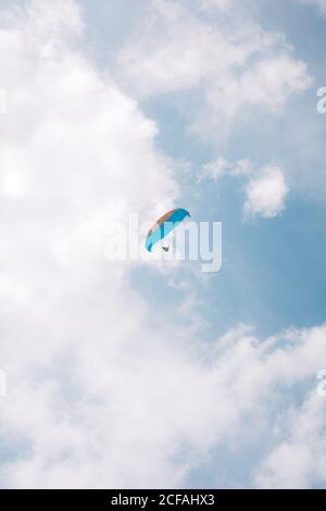 Von unten fliegen Menschen mit bunten Gleitschirmen in bewölktem Himmel In der Nähe der Durdle Door am Tag Stockfoto