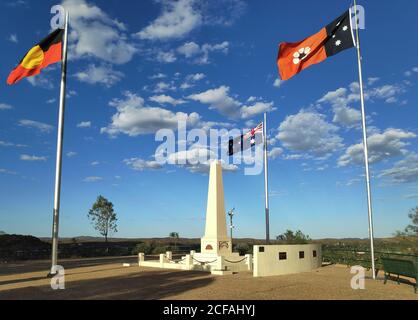 Flaggen flattern, vom Wind bewegt. Drei Flaggen aus Australien, dem Northern Territory und der Aborigine-Flagge. Obelisk Denkmal in der Mitte. Anzac Hill Memorial Stockfoto