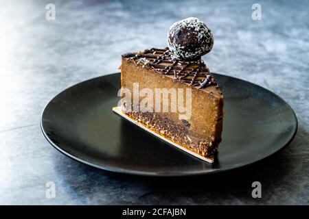 Roher Schokoladenkuchen mit Cashew und aromatisiert mit Datterobst für Paleo Diät. Gesundes Bio-Dessert ohne Zucker und Gluten frei in Black Plate. Stockfoto
