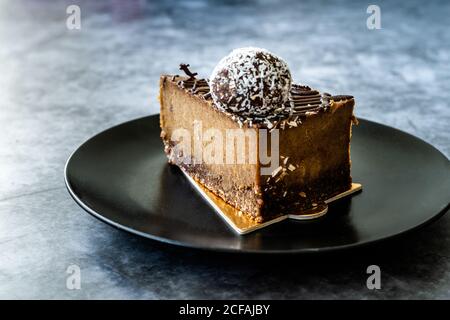 Roher Schokoladenkuchen mit Cashew und aromatisiert mit Datterobst für Paleo Diät. Gesundes Bio-Dessert ohne Zucker und Gluten frei in Black Plate. Stockfoto