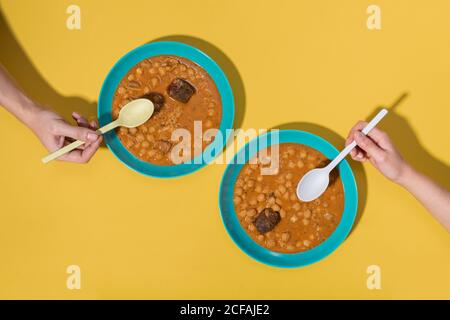 Draufsicht auf zwei Hände mit Callos Geschirr über Gelb Hintergrund Stockfoto