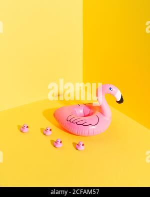 Bunte Komposition mit aufblasbarer Flamingo-Boje und Miniatur-Entenspielzeug Vor gelbem Hintergrund platziert Stockfoto