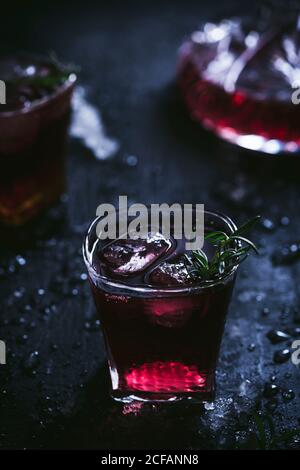 Karaffe und Kristallgläser mit Eis gefüllt mit Rotwein Auf schwarzem Tisch Stockfoto