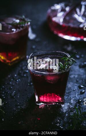 Karaffe und Kristallgläser mit Eis gefüllt mit Rotwein Auf schwarzem Tisch Stockfoto