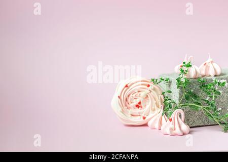 Rosa Meringues Nahaufnahme auf einem kreativen Podium aus Stein auf einem rosa Hintergrund. Handgefertigtes Baiser. Modernes Stillleben. Stockfoto