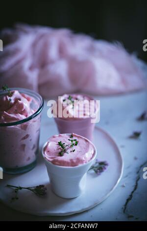 Leckere Gläser Erdbeermousse auf einem Tisch mit Löffel In der Nähe und mit Blumen geschmückt Stockfoto