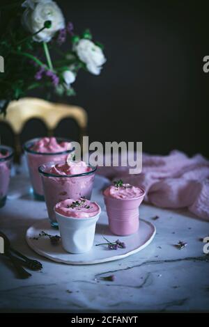 Leckere Gläser Erdbeermousse auf einem Tisch mit Löffel In der Nähe und mit Blumen geschmückt Stockfoto