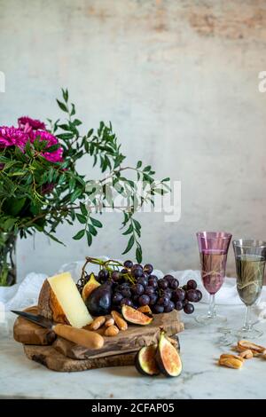 Affen neben einem Stück Käse auf Schneidebrettern in der Nähe Rosa Blüten Stockfoto