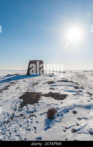 Einsames altes Steingebäude inmitten verschneiten Wüstengeländes Blauer Himmel mit heller Sonne Stockfoto