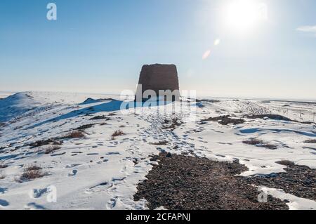 Einsames altes Steingebäude inmitten verschneiten Wüstengeländes Blauer Himmel mit heller Sonne Stockfoto