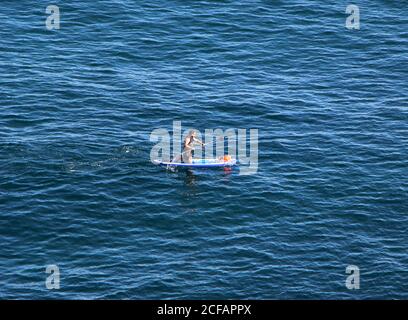 Ein einflüchtender Paddelboarder kniet auf dem Meer vor dem Cabo paddeln Menor kleines Kap Santander Kantabrien Spanien Stockfoto