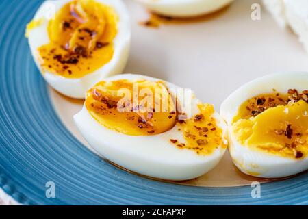 Gekochte Eier mit heißer Butter Chili Pepper Sauce. Halbgeschnittener Frühstücksteller. Gesunde Bio-Lebensmittel. Stockfoto