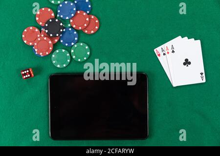Blick auf eine schwarze Tafel, Spielkarten, rote Würfel und bunte Spielsteine auf schlichter grüner Oberfläche Stockfoto