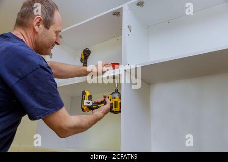Zimmermann installierte einen Küchenschrank Metallscharniere für Türen Stockfoto