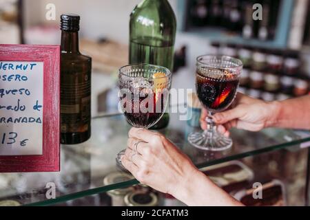 Kurzgeschnittene, nicht erkennbare Barkeeperin mit Gläsern, Tasse mit frischem Alkoholgetränk, während sie in einem lokalen Feinkostladen arbeitete Stockfoto