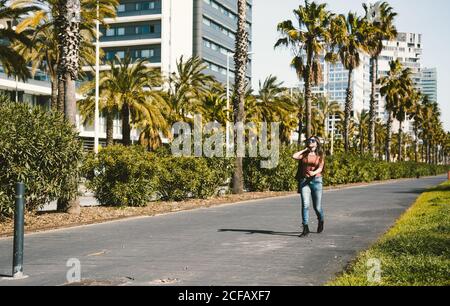 Junge Frau in Sonnenbrillen auf einem sonnigen Boulevard mit Palmen Stockfoto