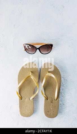 Draufsicht auf zwei Flip Flops in der Nähe trendy platziert Sonnenbrillen für den Sommerurlaub auf Putzoberfläche Stockfoto