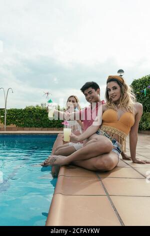 Eine Gruppe von Freunden, die eine Poolparty machen, während sie tanzen, lachen und Cocktails trinken Stockfoto