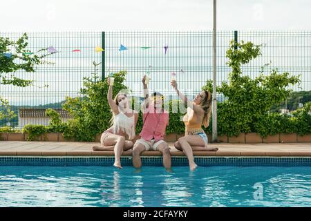 Eine Gruppe von Freunden, die eine Poolparty machen, während sie tanzen, lachen und Cocktails trinken Stockfoto