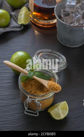 Von oben Glas kalter Mojito aus Rum und Limette mit Pfefferminze und braunem Zucker und auf nass gelegt Tisch in der Nähe von Eiswürfeln Stockfoto