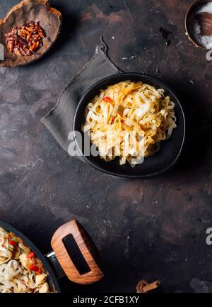 Draufsicht auf appetitlich würzige Pfannengerichte mit Huhn Fleisch und Gemüse auf Bratpfanne auf dunkel rustikal gelegt Tabelle Stockfoto