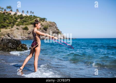 Anmutige acrobat führt mit Reifen am Strand Stockfoto